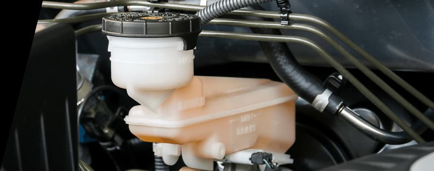 Brake master cylinder with translucent fluid reservoir and brake lines showing hydraulic brake system components