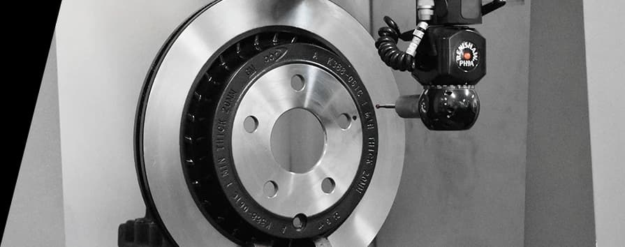 Black and white closeup of DBA brake rotor in manufacturing facility with specialized equipment positioned adjacent to the smooth disc surface