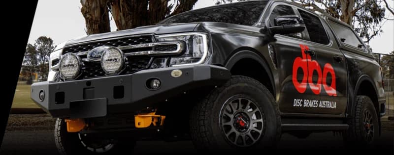 DBA Disc Brakes Australia branded dark pickup truck with red DBA logo and additional lighting equipment in outdoor setting