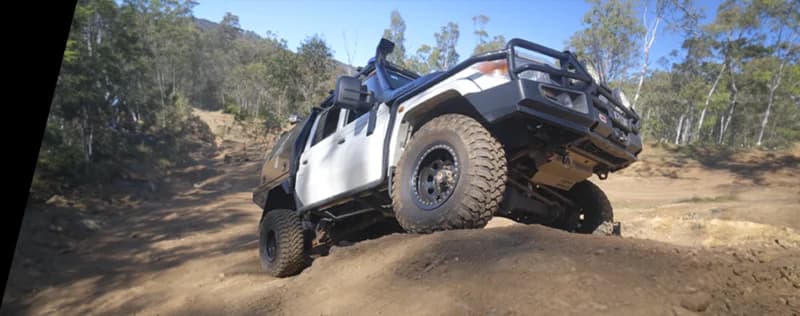 White 4WD vehicle positioned on steep sandy incline in Australian bush terrain demonstrating off-road capability
