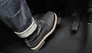 Assistant applying firm pressure on brake pedal during bleeding process to push fluid and air through the brake lines Close-up of person's foot pressing firmly on brake pedal during brake bleeding procedure to create hydraulic pressure in the system