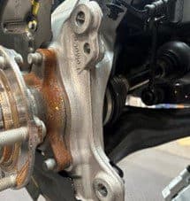 Step 4A: Inspecting OE hub casting for potential contact points with DBA caliper after backing plate modification Close-up of original equipment hub casting and modified backing plate showing potential contact points with DBA caliper during installation