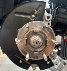Step 3B: Modified backing plate reinstalled on vehicle for test fitting of DBA 6-pot caliper after clearance cuts Modified backing plate reinstalled on vehicle hub with clearance cuts completed for proper fitment of DBA 6-pot caliper upgrade